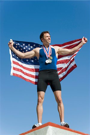 Male athlete on winner's podium, holding up American flag Stock Photo - Premium Royalty-Free, Code: 632-05760512
