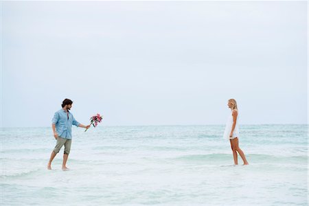 Couple walking on water towards each other, man holding out bouquet Stock Photo - Premium Royalty-Free, Code: 632-05760531