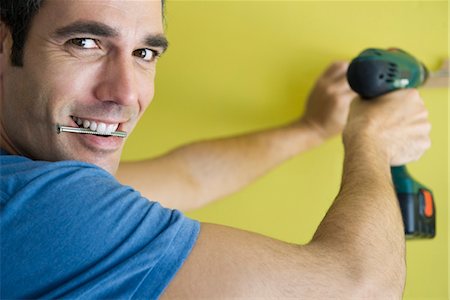 drilling wall - Man using power drill, biting screw in mouth Stock Photo - Premium Royalty-Free, Code: 632-05760684