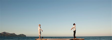 dock side view - Couple standing back to back on pier, arms out stretched and eyes closed Stock Photo - Premium Royalty-Free, Code: 632-05760730