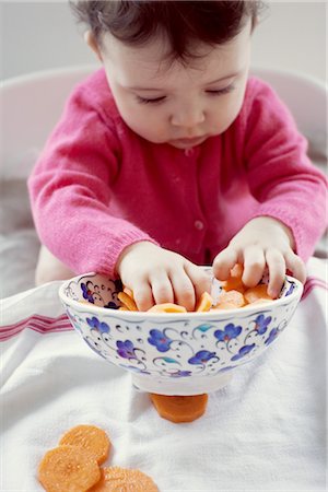 Infant playing with bowl of carrots Stock Photo - Premium Royalty-Free, Code: 632-05760759