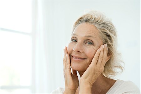 Mature woman touching cheeks, smiling, portrait Stock Photo - Premium Royalty-Free, Code: 632-05816229