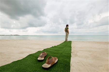 Man standing at end of carpet on beach, sandals on foreground Stock Photo - Premium Royalty-Free, Code: 632-05816249
