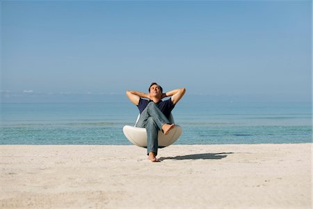 Mid-adult man relaxing in armchair on beach with eyes closed Stock Photo - Premium Royalty-Free, Code: 632-05816289