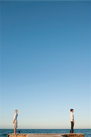 problem - Couple standing back to back on pier, side view Stock Photo - Premium Royalty-Free, Code: 632-05816343