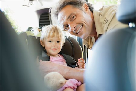 person in car interior - Father fastening little girl into car seat, both smiling at camera Stock Photo - Premium Royalty-Free, Code: 632-05816742