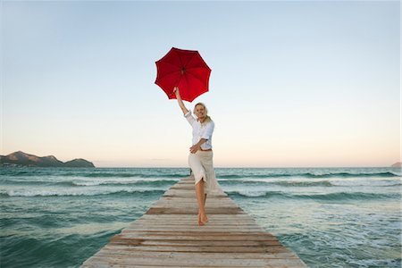 sun umbrella - Young woman jumping on pier holding umbrella Stock Photo - Premium Royalty-Free, Code: 632-05816791