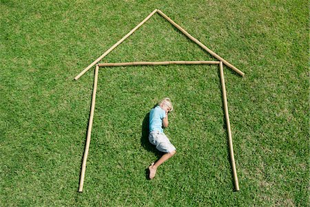 safety home - Boy lying on grass within outline of house, high angle view Stock Photo - Premium Royalty-Free, Code: 632-05816839