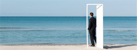 panoramic beach - Businessman standing on beach looking at ocean, seen through open door Stock Photo - Premium Royalty-Free, Code: 632-05816884