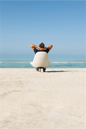 simsearch:632-05816128,k - Homme assis dans le fauteuil sur la plage en regardant l'océan, vue arrière Photographie de stock - Premium Libres de Droits, Code: 632-05817026