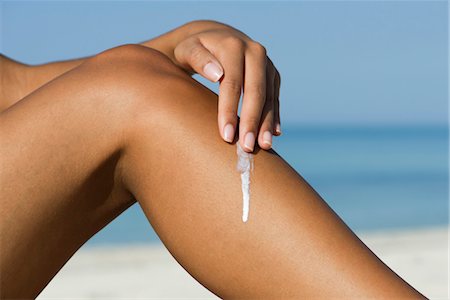 simsearch:632-05845423,k - Woman applying sunscreen to leg at the beach, cropped Stock Photo - Premium Royalty-Free, Code: 632-05845038