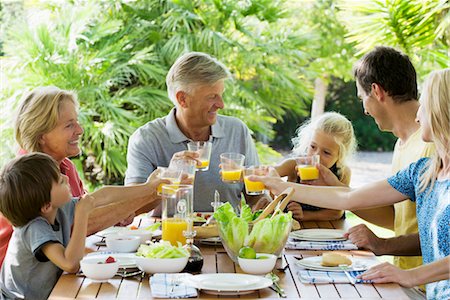 family and meal - Multi-generation family toasting with orange juice outdoors, portrait Stock Photo - Premium Royalty-Free, Code: 632-05845110