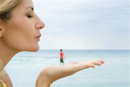 Woman appearing to blow a kiss at tiny man standing on her hand Foto de stock - Sin royalties Premium, Código: 632-05845157