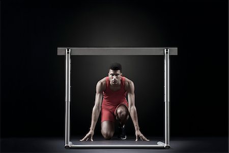 Male athlete at starting position in front of hurdle Stock Photo - Premium Royalty-Free, Code: 632-05845355