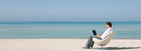 Man using laptop computer at the beach Stock Photo - Premium Royalty-Free, Code: 632-05845395