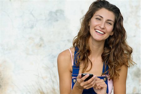 salopette - Texte de la jeune femme messagerie, souriant à la caméra Photographie de stock - Premium Libres de Droits, Code: 632-05845403