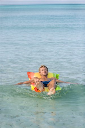 simsearch:632-05816834,k - Young man relaxing on pool raft in sea Foto de stock - Sin royalties Premium, Código: 632-05845456