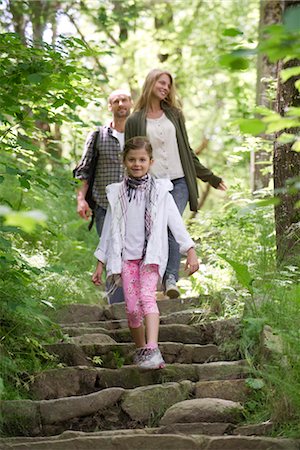 Girl walking down stone steps in woods, parents in background Foto de stock - Sin royalties Premium, Código: 632-05845608