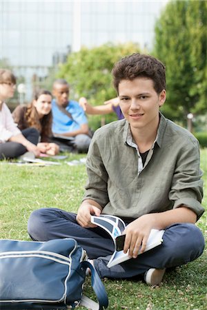 female friends sitting on ground - Young man sitting on grass, people in background, portrait Stock Photo - Premium Royalty-Free, Code: 632-05845653