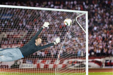 Soccer goalkeeper diving to block ball Foto de stock - Sin royalties Premium, Código: 632-05991202