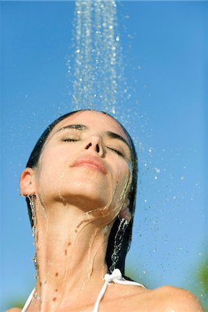 Mid-adult woman under shower outdoors with eyes closed Stock Photo - Premium Royalty-Free, Code: 632-05991276