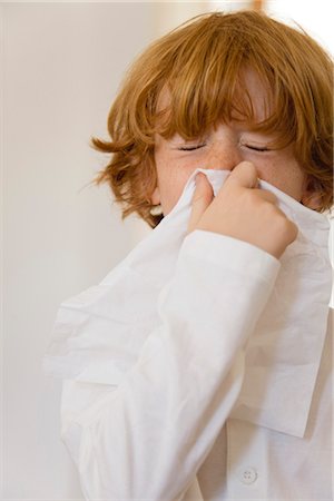 Boy blowing nose on tissue with eyes closed Foto de stock - Royalty Free Premium, Número: 632-05991290