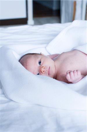 Newborn baby lying on bed, looking at camera Stock Photo - Premium Royalty-Free, Code: 632-05991359