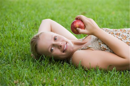 person lying on back hands behind head - Young woman lying on grass holding apple Stock Photo - Premium Royalty-Free, Code: 632-05991381