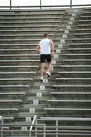 people in stadium bleachers - Man running up steps in stadium, rear view Stock Photo - Premium Royalty-Free, Code: 632-05991400