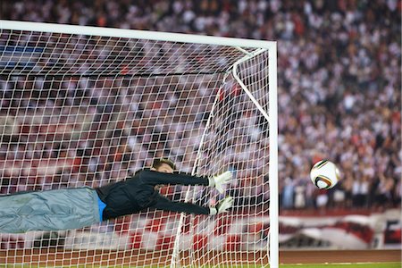 Soccer goalkeeper diving to guard net Foto de stock - Sin royalties Premium, Código: 632-05991401