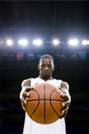 playing basketball - Basketball player holding basketball, focus on foreground Stock Photo - Premium Royalty-Free, Code: 632-05991412