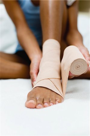 Woman wrapping bandage around injured ankle, low section Foto de stock - Sin royalties Premium, Código: 632-05991495