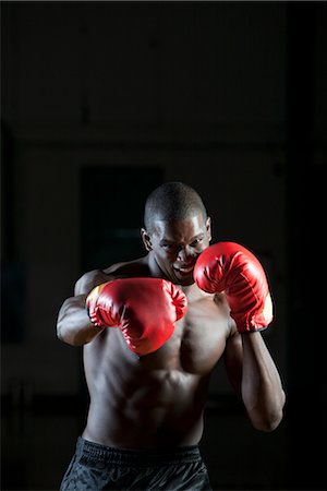 Boxer wearing boxing gloves in fighting stance, portrait Stock Photo - Premium Royalty-Free, Code: 632-05991707