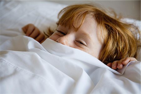 Boy lying in bed with bed sheet covering face Stock Photo - Premium Royalty-Free, Code: 632-05991729