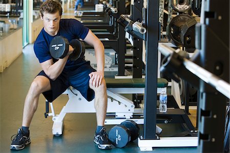 simsearch:632-05991605,k - Young man lifting dumbbell in weight room Foto de stock - Royalty Free Premium, Número: 632-05992083