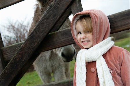 Little girl posing for picture with donkey behind fence, portrait Foto de stock - Sin royalties Premium, Código: 632-05992279