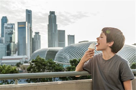 Boy eating ice cream cone, city skyline in background Foto de stock - Sin royalties Premium, Código: 632-06029449