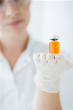 Scientist holding vial containing orange liquid Stock Photo - Premium Royalty-Free, Code: 632-06029469