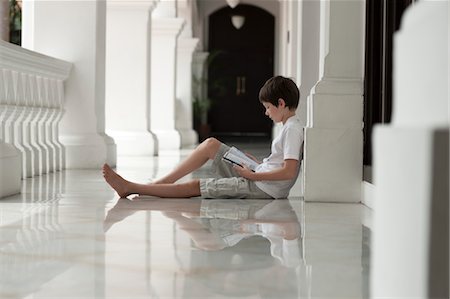 photos of boys short pants - Boy sitting on floor of veranda reading book Stock Photo - Premium Royalty-Free, Code: 632-06029533