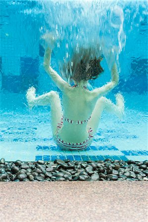 simsearch:632-06030001,k - Girl swimming underwater in swimming pool, rear view Stock Photo - Premium Royalty-Free, Code: 632-06029548