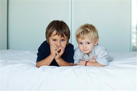 siblings - Young brothers lying on bed side by side, portrait Stock Photo - Premium Royalty-Free, Code: 632-06029617