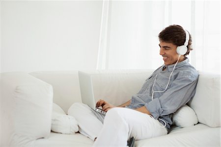 Mature man using laptop computer on sofa wearing headphones Stock Photo - Premium Royalty-Free, Code: 632-06029626