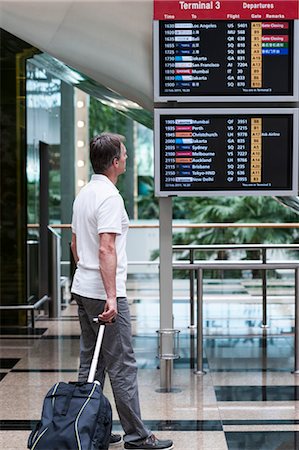 Man looking at arrival departure board in airport Stock Photo - Premium Royalty-Free, Code: 632-06029712