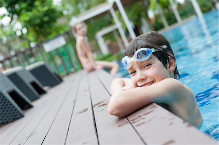 Boy with goggles leaning on edge of swimming pool, smiling Foto de stock - Sin royalties Premium, Código: 632-06029834