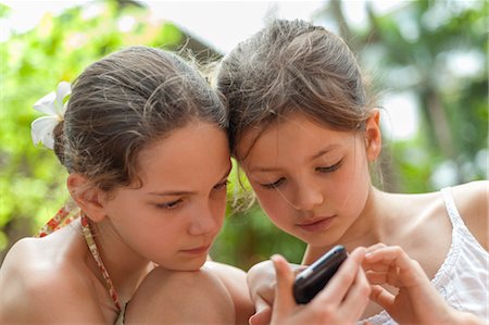 Sisters looking at cell phone together Stock Photo - Premium Royalty-Free, Code: 632-06029852