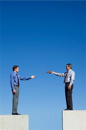 Businessmen standing on platforms, one handing the other a tiny factory Foto de stock - Sin royalties Premium, Código: 632-06029946