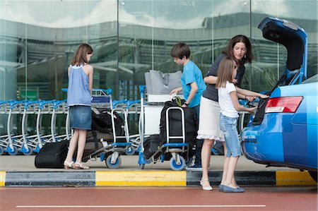 Family outside of airport unloading luggage from taxi trunk Stock Photo - Premium Royalty-Free, Code: 632-06030172