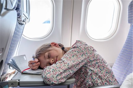 sleeping by the window - Girl resting head on tray table on airplane Stock Photo - Premium Royalty-Free, Code: 632-06030201