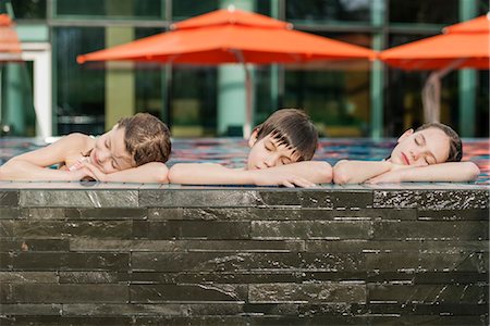 Siblings leaning on edge of swimming pool side by side, heads resting on arms Stock Photo - Premium Royalty-Free, Code: 632-06030269