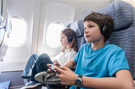 Boy using remote control to change channels on airplane Stock Photo - Premium Royalty-Free, Code: 632-06030272